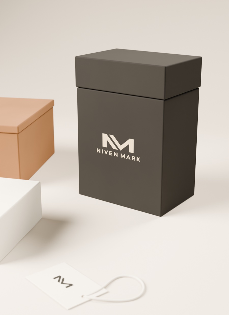 Detalle del cartón rígido carbón con tapa, el logotipo Niven Mark en crema y la etiqueta colgante con el monograma.